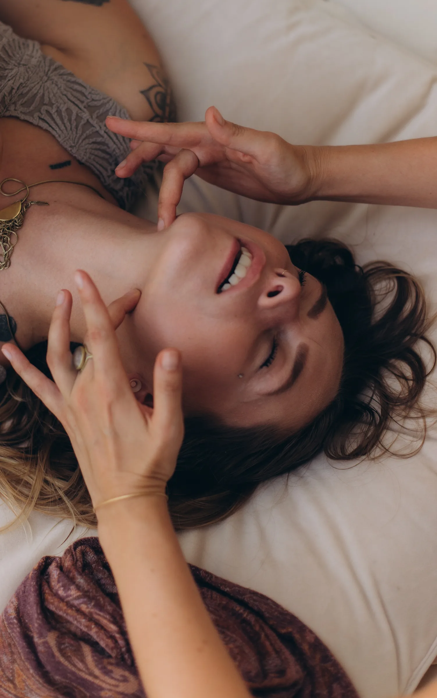 A client smiling with her eyes closed, hands at her face